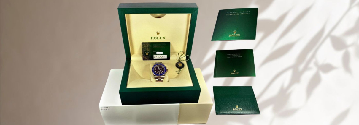 Rolex 'Cookie Monster' Submariner watch displayed in its original green box with warranty card and booklets, showcasing the blue and black bezel design.