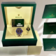 Rolex 'Cookie Monster' Submariner watch displayed in its original green box with warranty card and booklets, showcasing the blue and black bezel design.